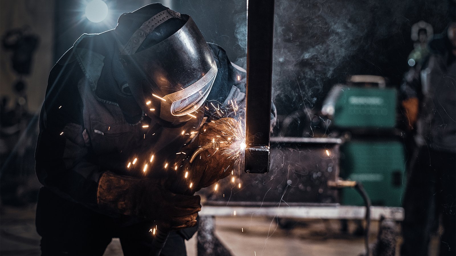 Man is working at metal factory, he is welding a piece of rail using special tools.